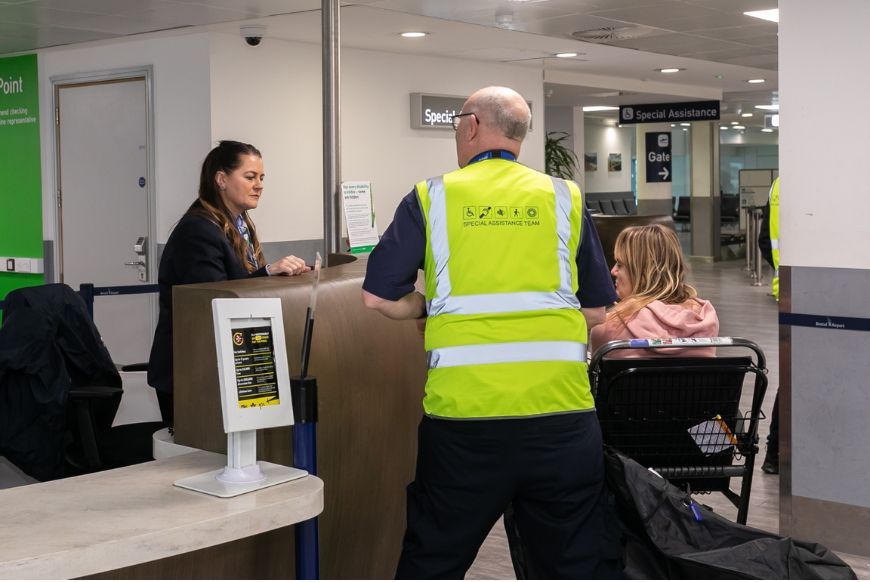 check in desk at airport, woman helping lady in a wheelchair